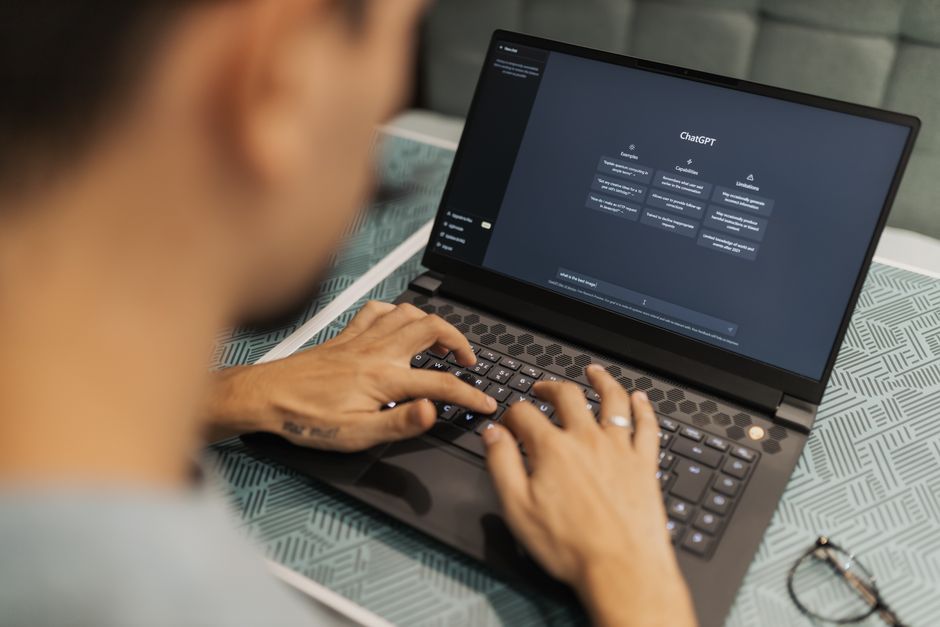 Una persona concentrada escribe en un portátil que ejecuta software de IA en el interior.