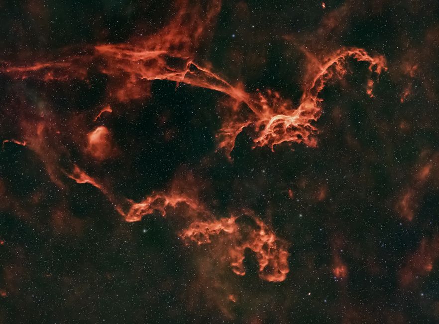 Una nebulosa roja vibrante rodeada de estrellas, destacando el cosmos infinito.