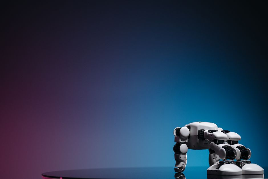 Un primer plano de un juguete robot futurista sobre una superficie reflectante con un fondo degradado.