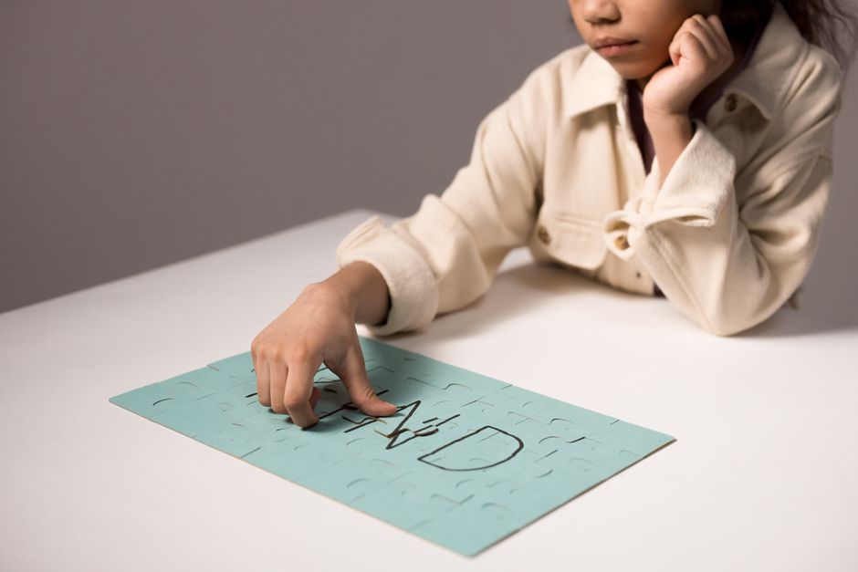 Un niño pequeño resolviendo un rompecabezas azul, participando en un juego reflexivo en una mesa.