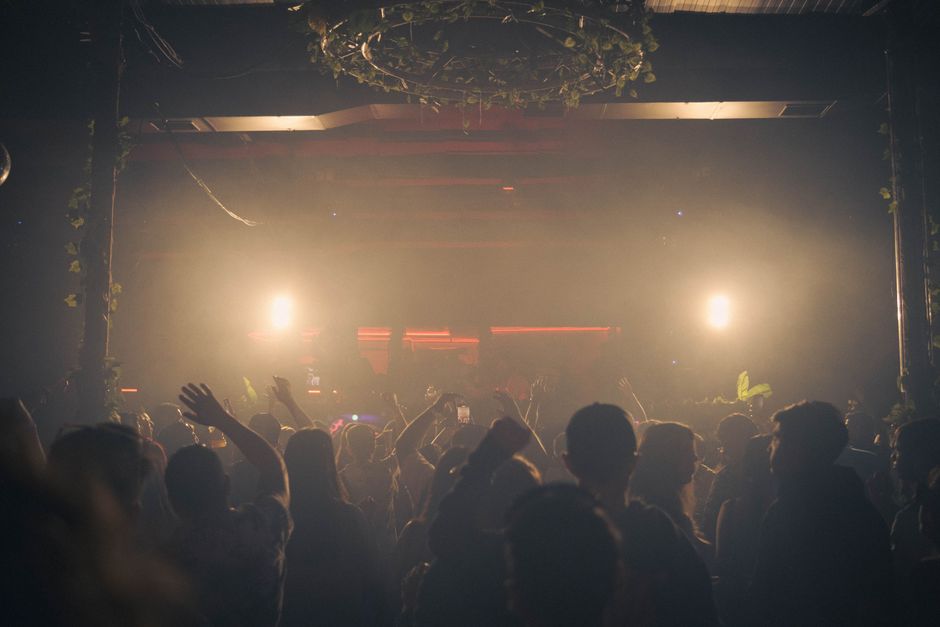 Escena dinámica de club nocturno con una multitud disfrutando de la música bajo luces brillantes, creando una atmósfera animada.