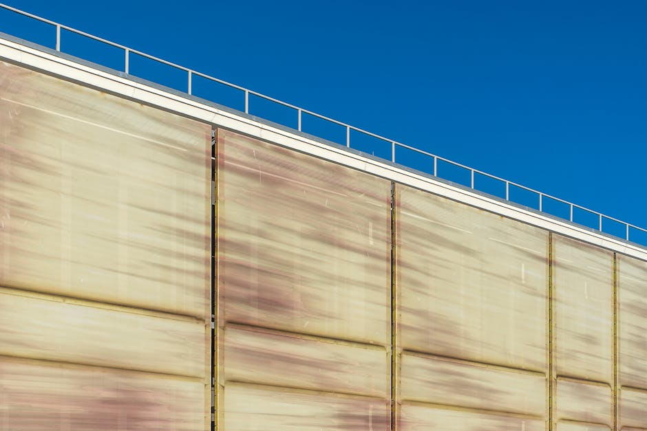 Primer plano de la fachada metálica rústica de un edificio industrial bajo un cielo azul claro.
