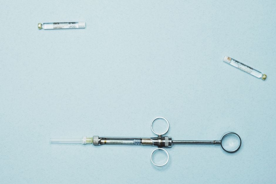 Foto de stock de alta calidad de una jeringa dental y viales sobre un fondo azul. Ideal para odontología.