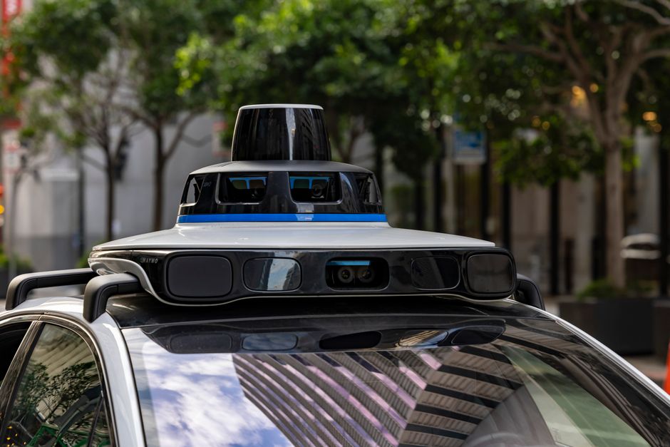 Vista detallada de los sensores en la parte superior de un automóvil autónomo, que muestra tecnología avanzada en un entorno urbano.