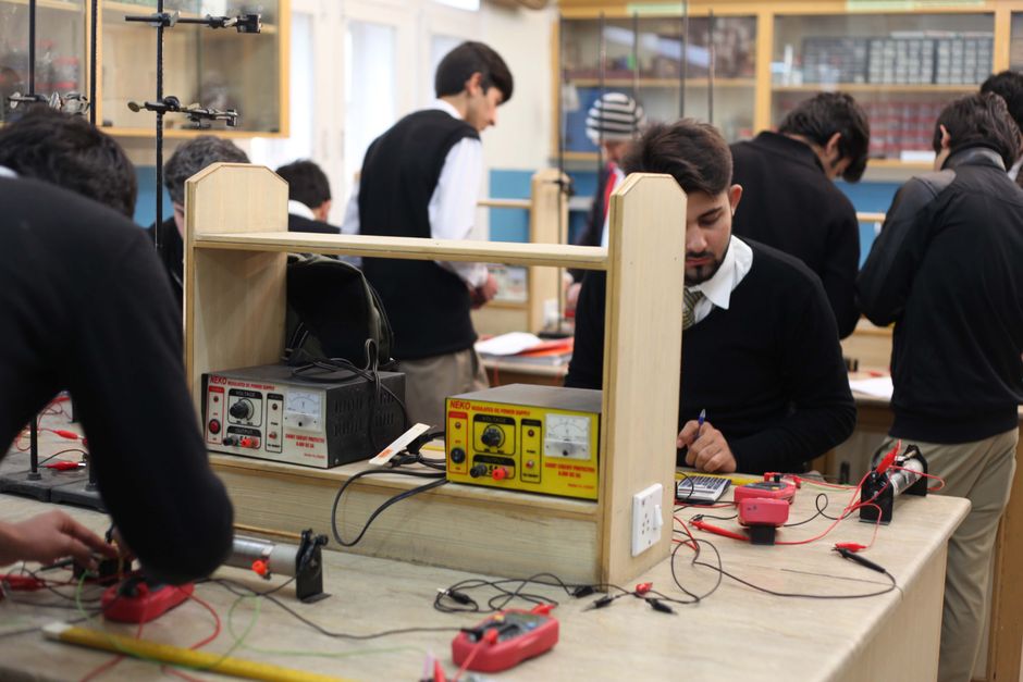 Estudiantes trabajando en proyectos de electrónica en un laboratorio, centrándose en el aprendizaje práctico.