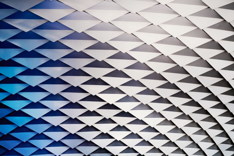 Techo geométrico abstracto con estructuras blancas e iluminación degradada azul.
