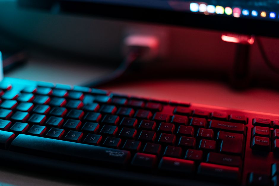 Una vista cercana vibrante de un teclado de computadora iluminado por luz roja y azul, enfatizando temas tecnológicos.