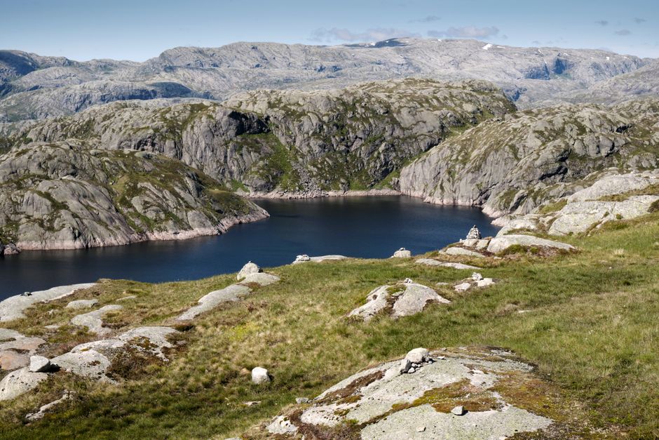 Un paisaje montañoso sereno con un lago tranquilo rodeado de acantilados escarpados y terreno de hierba.