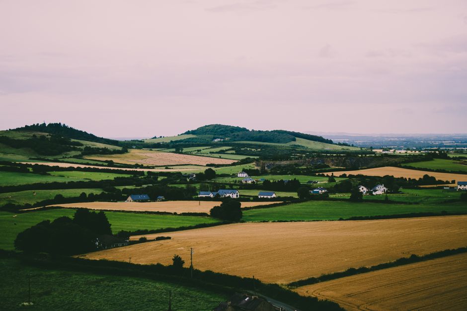 Paisaje escénico de Irlanda con campos verdes, colinas suaves y casas rurales.