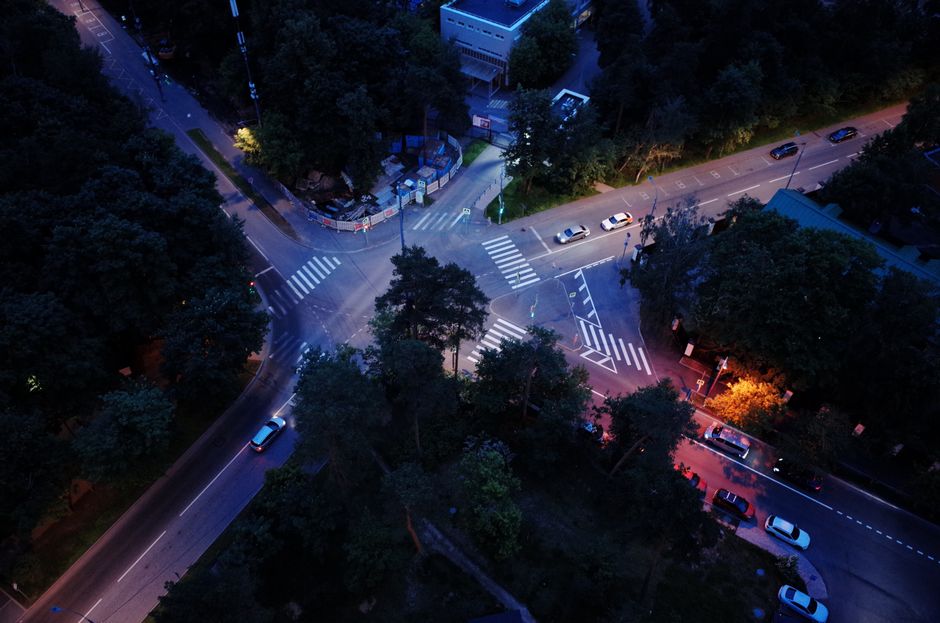 Una perspectiva aérea que captura una vibrante intersección de calles de la ciudad iluminada por farolas durante la noche.