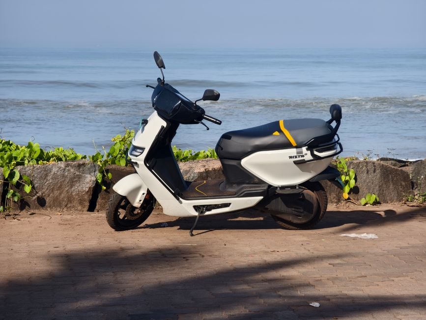 Un moderno patinete eléctrico aparcado junto al mar con un pintoresco paisaje costero de fondo.