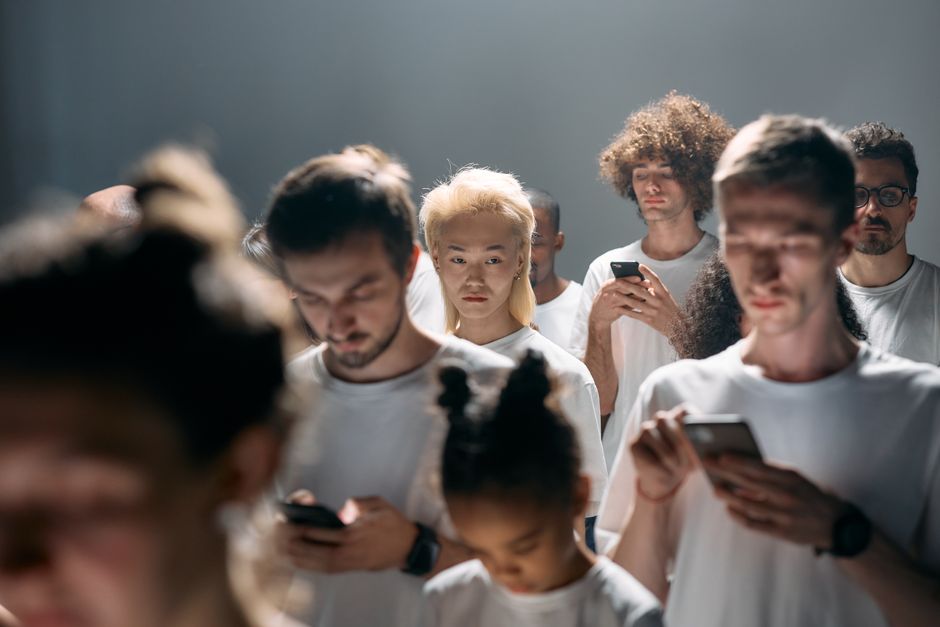 Un grupo diverso de personas mirando teléfonos inteligentes, ilustrando el aislamiento social en la tecnología moderna.
