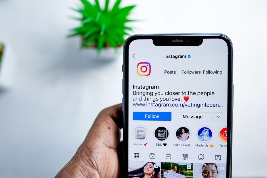 Mano sostiene un smartphone con el perfil de Instagram visible.
