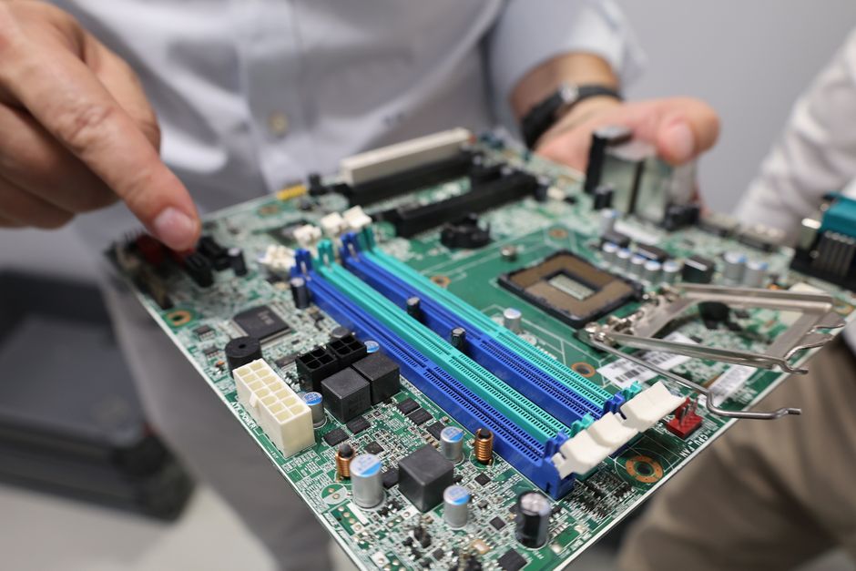 Primer plano de un técnico manipulando una placa base de ordenador, haciendo hincapié en la tecnología y la electrónica.