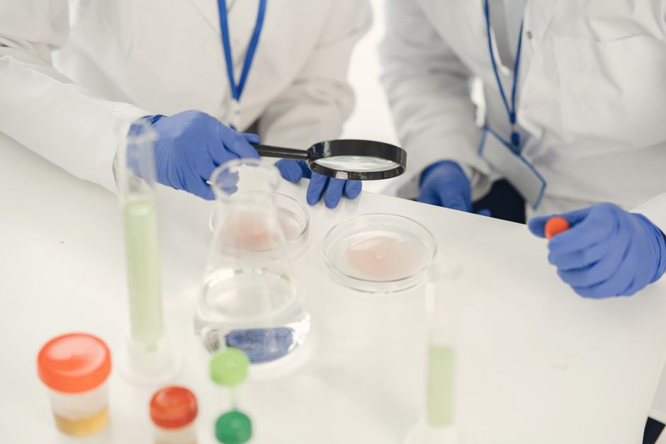 Investigadores con batas examinando muestras y realizando experimentos con tubos de ensayo y placas de Petri.