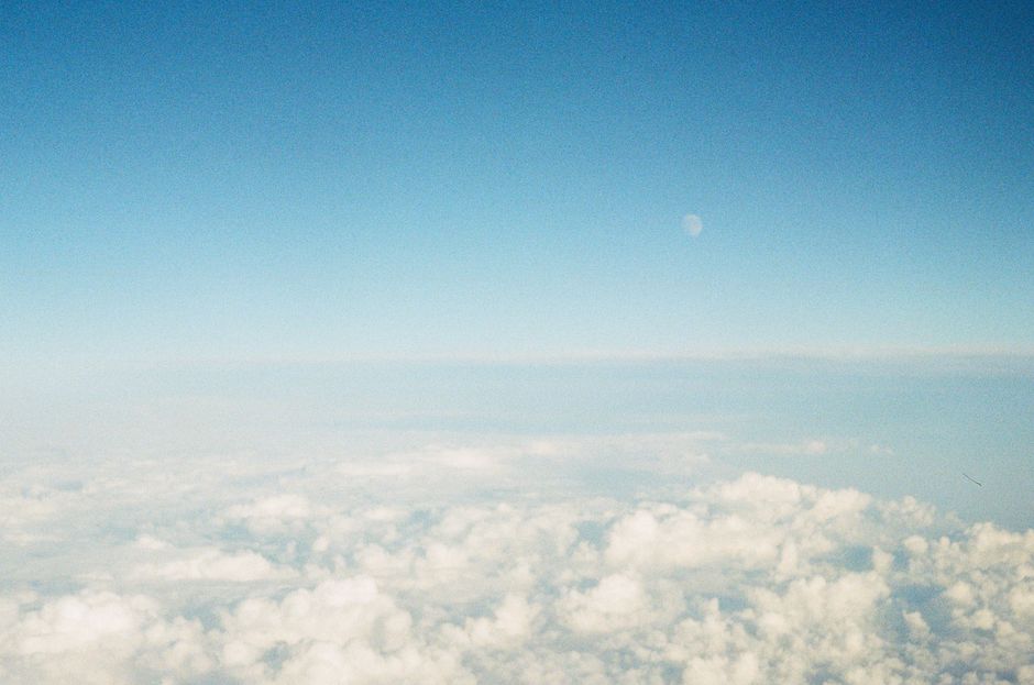 Una vista impresionante de un cielo azul claro con la luna creciente sobre nubes blancas y esponjosas.