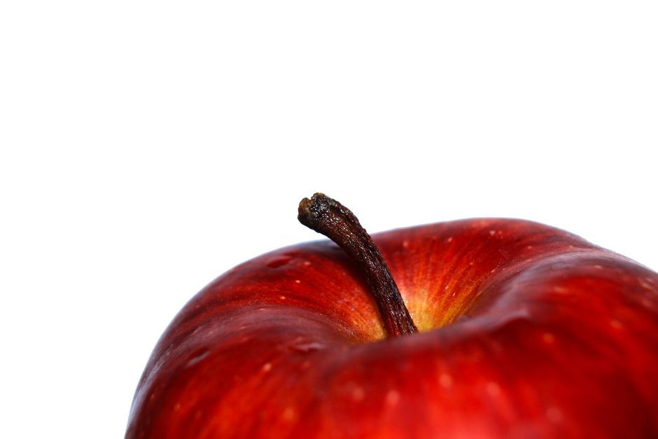 Una vista detallada de una manzana roja fresca contra un fondo blanco, que muestra su belleza natural.