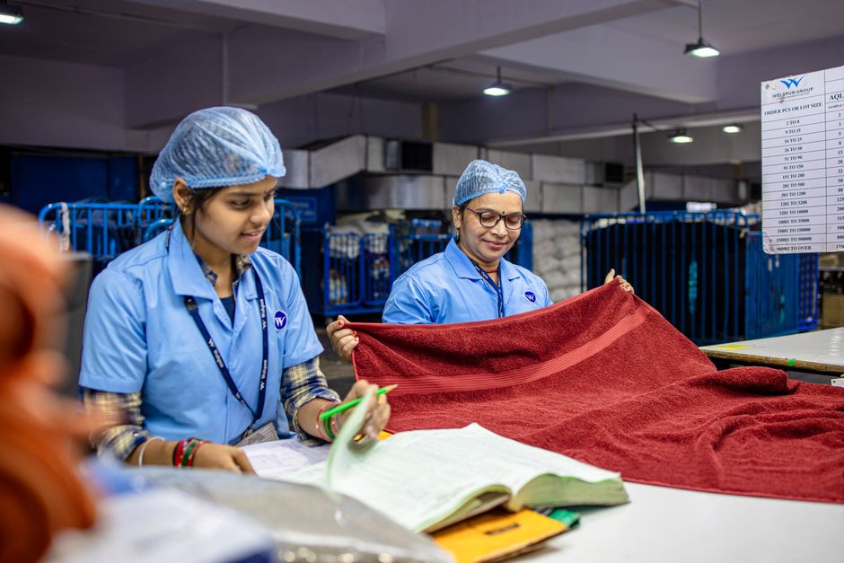 Dos trabajadoras textiles inspeccionando tela roja en un entorno de fábrica.