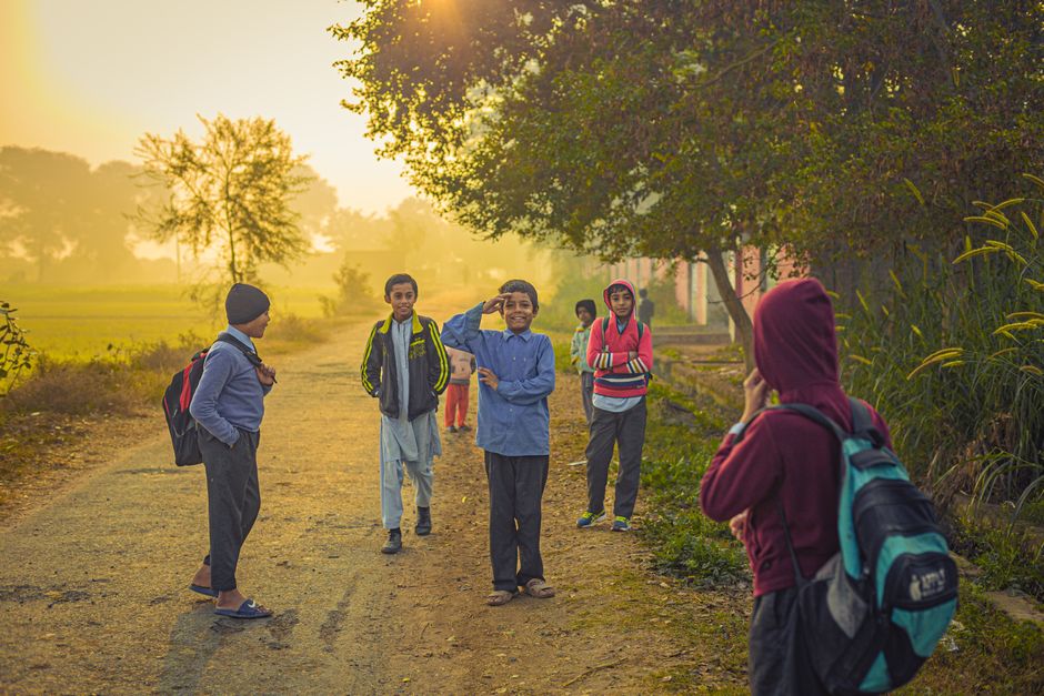Niños caminando hacia la escuela en una mañana brumosa en el Pakistán rural, mostrando camaradería e inocencia.