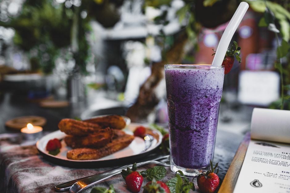 Indulgente batido de arándano con churros en un acogedor ambiente de cafetera, perfecto para un dulce capricho.