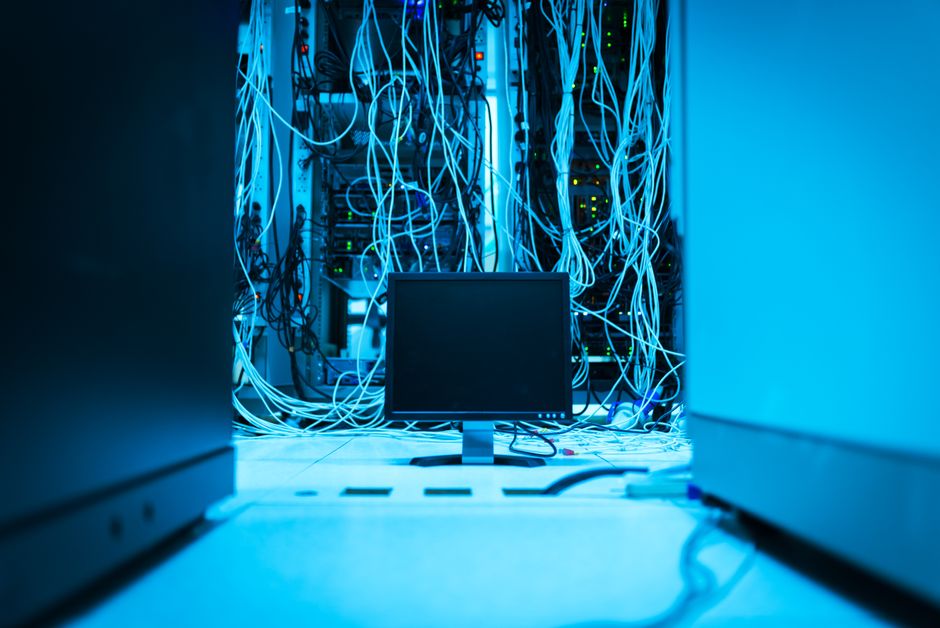 Una red compleja de cables en un centro de datos con un monitor en primer plano.