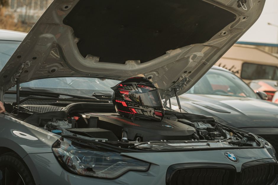 Primer plano del capó de un automóvil abierto con un casco de carreras colocado sobre el motor en Erbil, Irak.