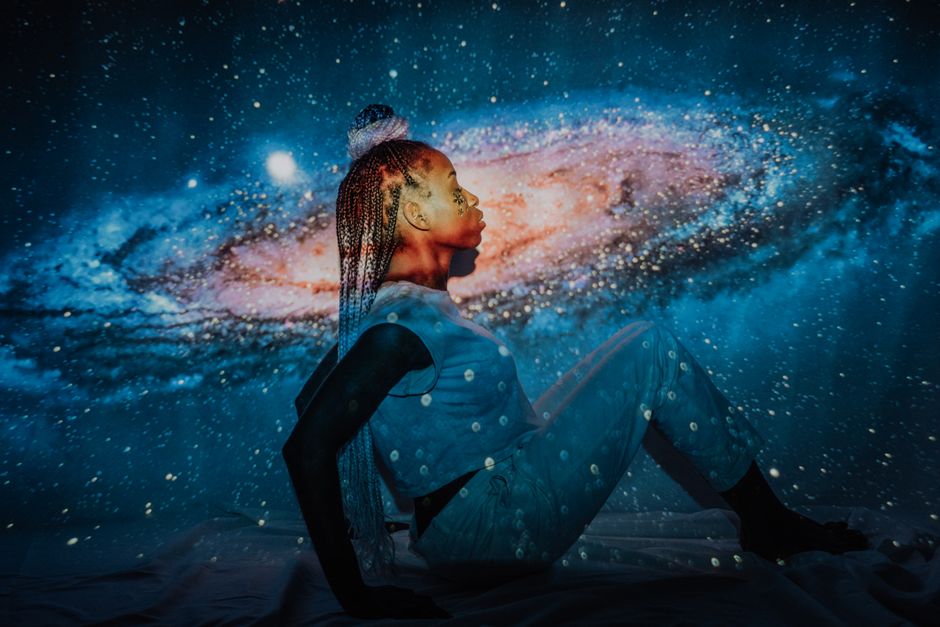 Retrato impactante de una mujer con un fondo proyectado de galaxia estrellada, que transmite misticismo.