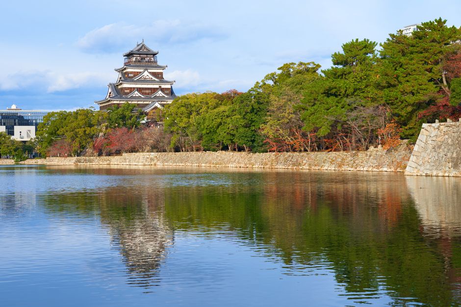 La arquitectura tradicional del Castillo de Hiroshima reflejada hermosamente en las aguas serenas y los frondosos árboles verdes.