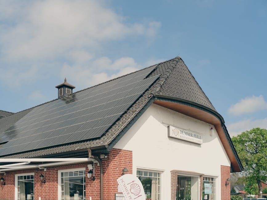 Un edificio de ladrillo rojo con paneles solares en el techo, bajo un cielo azul claro, que simboliza la sostenibilidad y la energía renovable.