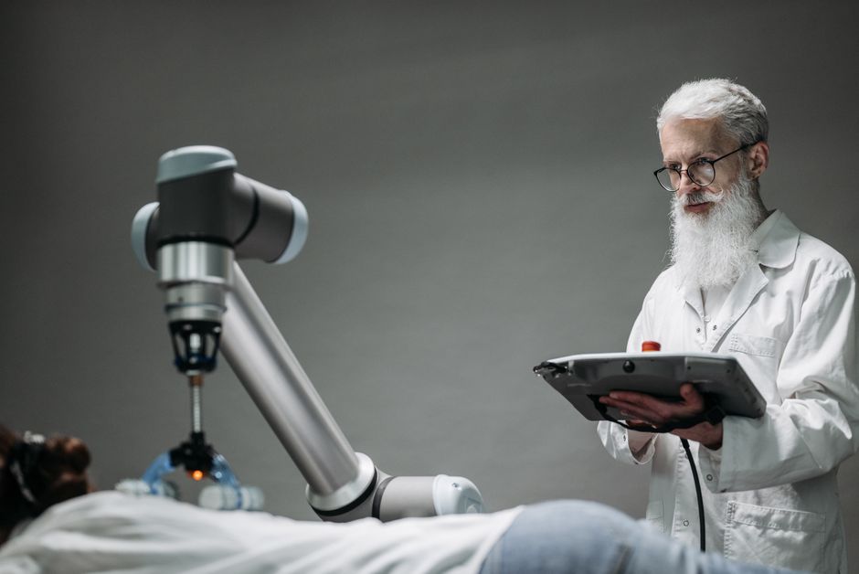 Científico senior observando cómo un robot realiza una tarea en interiores.