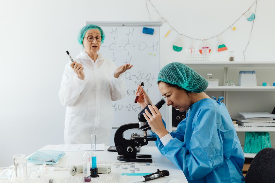 Dos científicas llevando a cabo investigación con un microscopio en un entorno de laboratorio.
