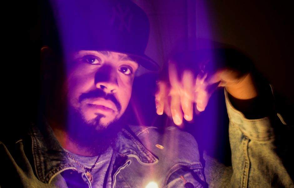 Retrato de un hombre con un gorro, iluminado por luz púrpura.