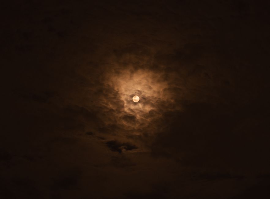 Una dramática luna llena rodeada de nubes oscuras y melancólicas en el cielo nocturno.
