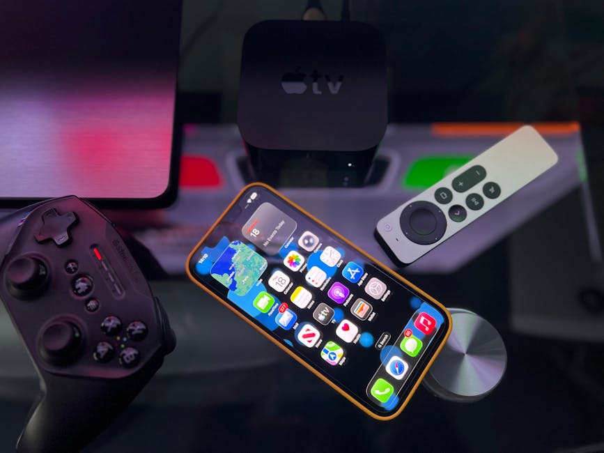 Elegante configuración de entretenimiento doméstico que incluye un iPhone, un Apple TV y un controlador de juegos sobre una superficie oscura.