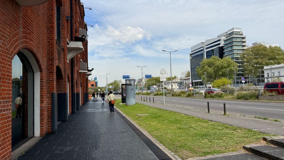 Calle de la ciudad con edificios de ladrillo rojo y modernos rascacielos bajo un cielo azul.