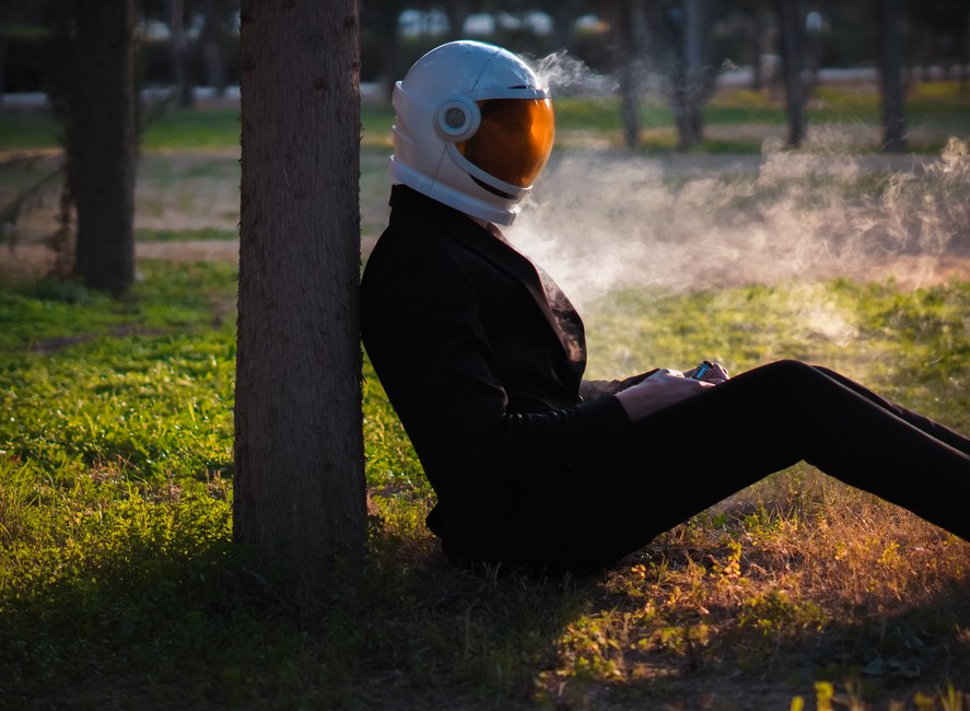Un astronauta solitario con traje fuma al aire libre, sereno, al atardecer.