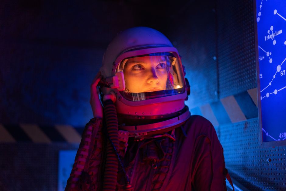 Un astronauta futurista en un traje espacial observa el mapa estelar, rodeado de una iluminación vibrante.
