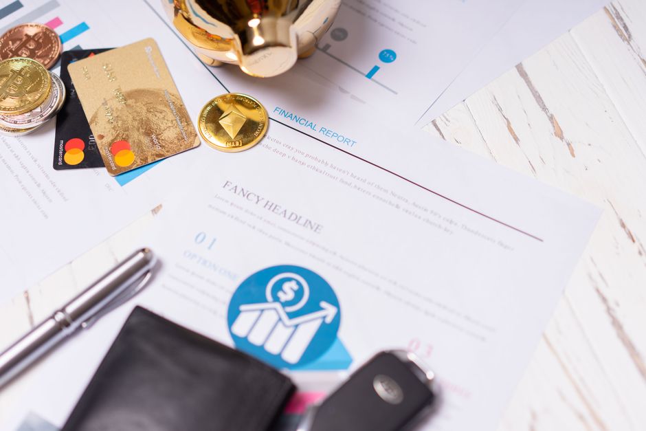 Primer plano de documentos financieros, tarjetas de crédito, monedas y un bolígrafo sobre un escritorio de madera.