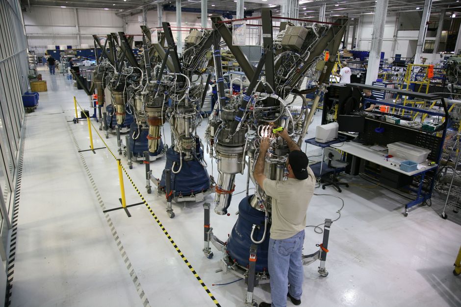 Un técnico inspecciona la maquinaria del motor de cohete dentro de una fábrica industrial moderna.