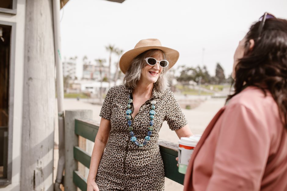 Dos mujeres elegantes charlando al aire libre, mostrando moda de verano y alegría.