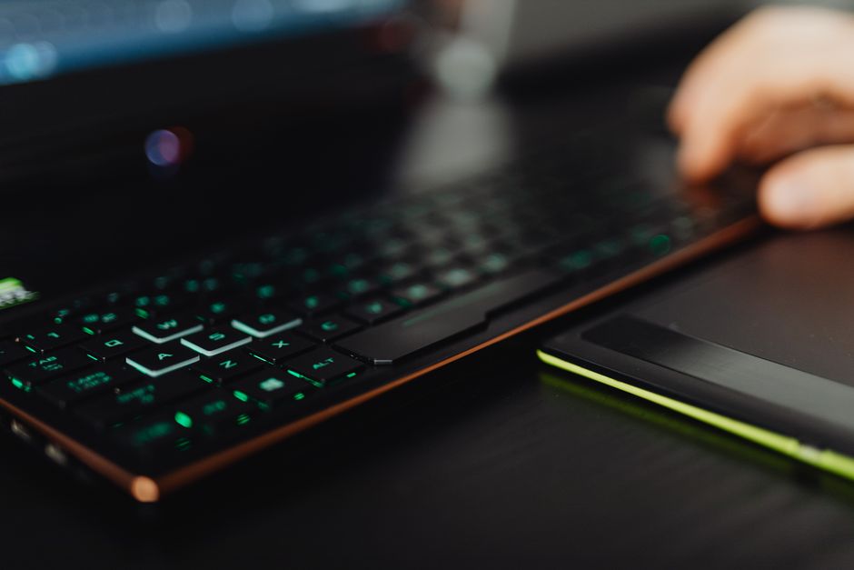 Un primer plano de un teclado de juego retroiluminado y laptop, resaltando el uso de tecnología moderna.