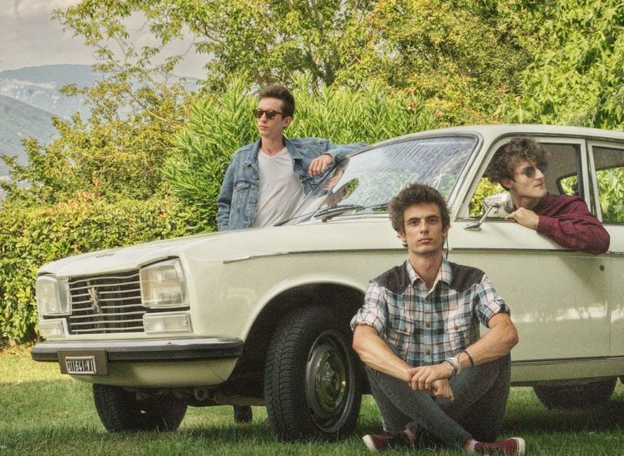 Tres hombres posando con un coche vintage al aire libre en Vicenza, Italia.