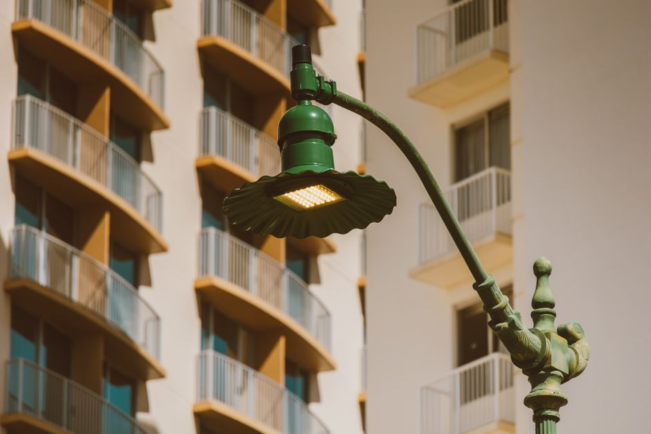 Primer plano de una farola verde vintage contra un fondo de arquitectura residencial moderna.