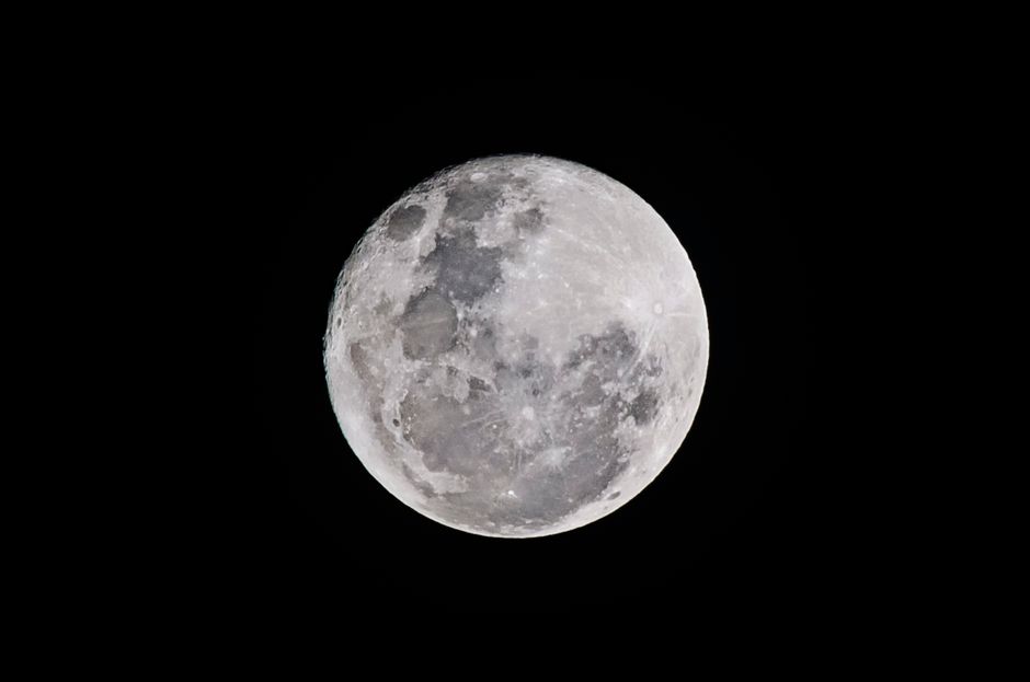 Luna llena detallada capturada contra un cielo negro, mostrando texturas lunares.