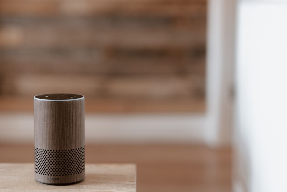 Un elegante altavoz inteligente se encuentra sobre una superficie de madera en un acogedor y cálido entorno interior.