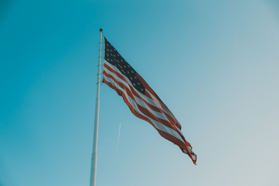 Vista en ángulo bajo de la bandera americana ondeando en un día ventoso contra un cielo azul claro.