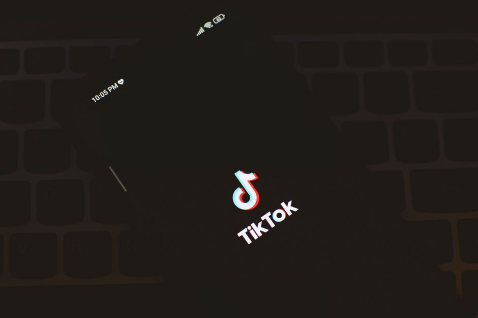 Acercamiento de un smartphone mostrando el logotipo de la aplicación TikTok sobre un fondo de teclado oscuro.