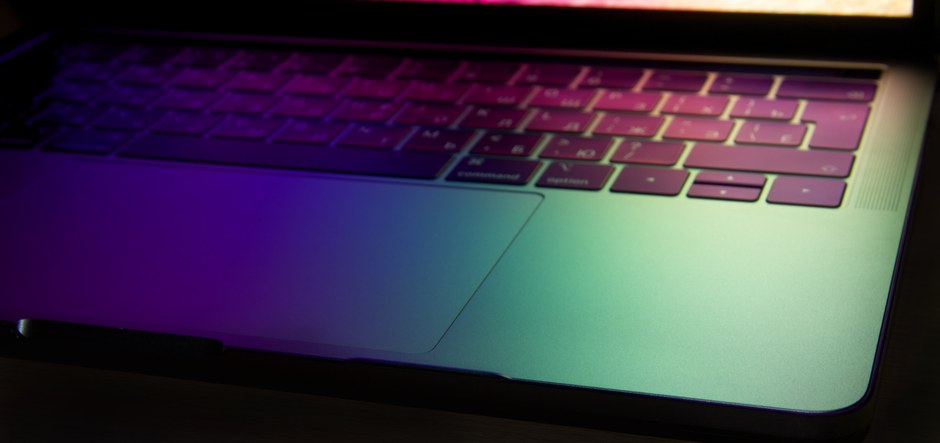 Teclado vibrante y moderno de portátil iluminado con colores neón, mostrando un resplandor tecnológico.