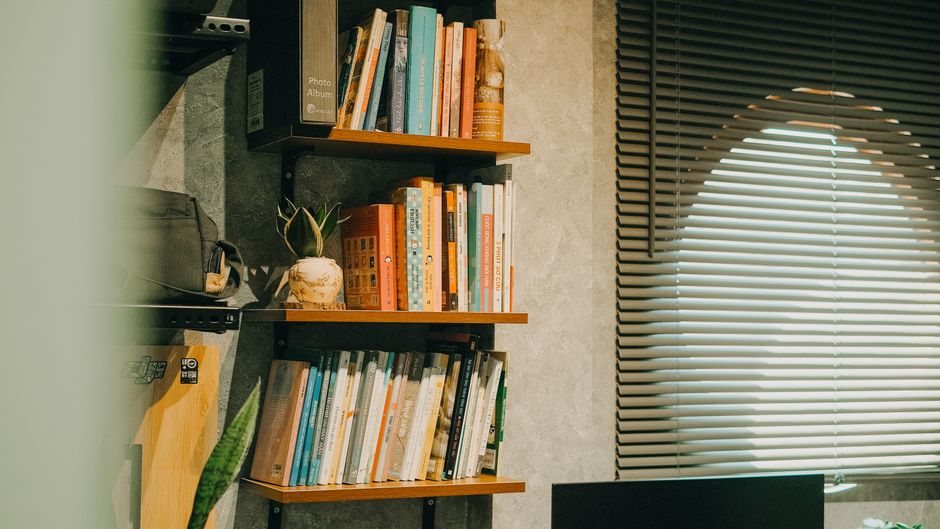 Estantería con varios libros en un despacho bien iluminado, en un ambiente cálido.
