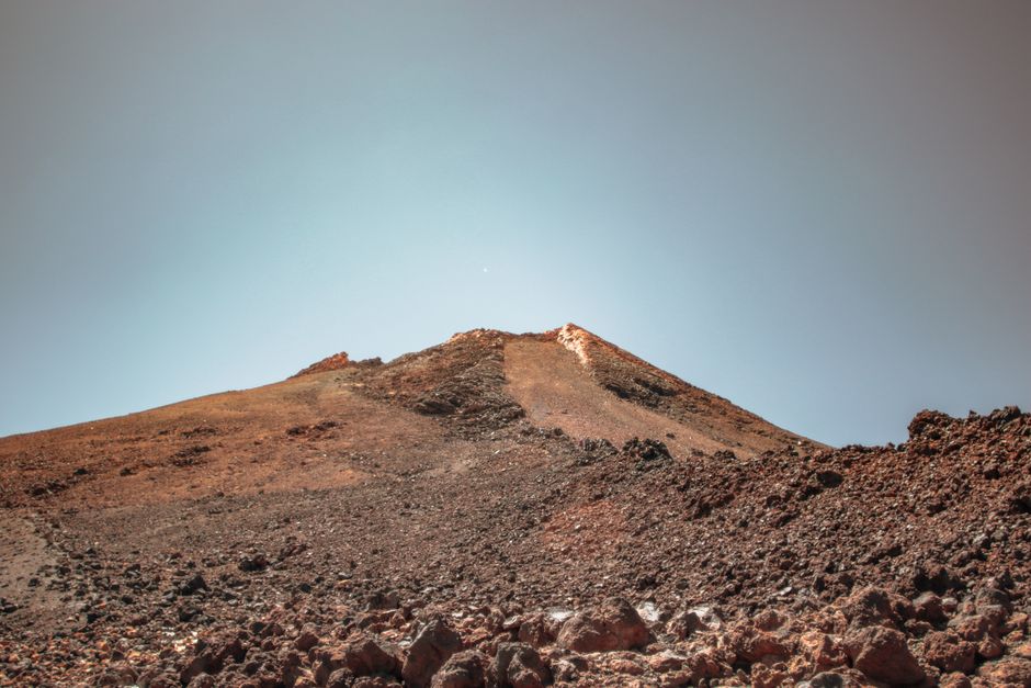 Una montaña rocosa y árida bajo un cielo azul claro, mostrando la belleza rugged de la naturaleza.